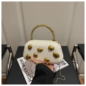 Close-up of white structured evening bag with gold pebble accents and unique metal handle