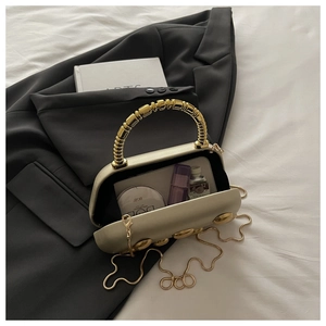 Detail of champagne gold hard shell evening bag showing interior space and makeup items