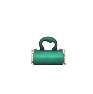 Détail macro du mini sac cylindrique vert foncé avec chaîne dorée et texture mate