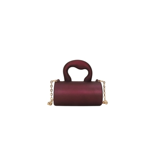 Détails d'un mini sac cylindrique bordeaux avec poignée épaisse et chaîne dorée