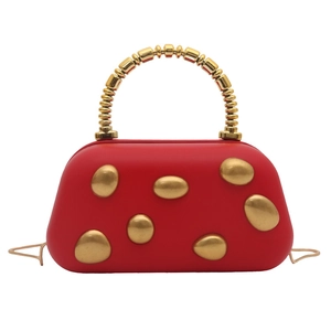 Detail of red hard shell evening bag with golden metallic patches and beaded handle