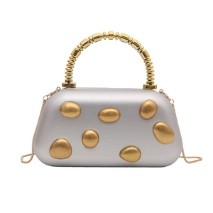 Detail of silver matte box bag with gold pebble accents and creative beaded metal handle