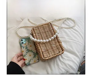 Detail of woven straw handbag with large pearl top handle and matching chain strap