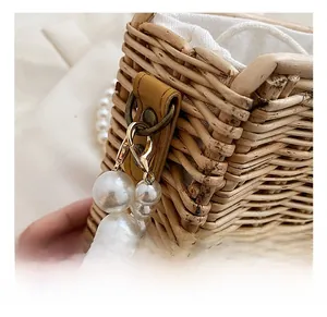 Detailed macro view of woven straw bag with pearl strap and golden snap hooks