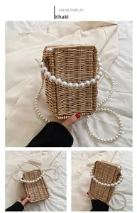 Detailed macro view of khaki woven straw box bag with decorative large pearl handle straps