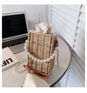 Detail of woven straw bag with pearl handle, drawstring liner, and textured finish