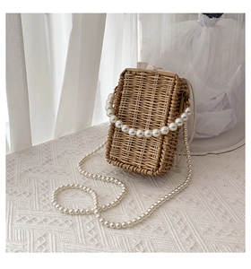 Detailed shot of woven straw bag with pearl handle and drawstring lining on lace