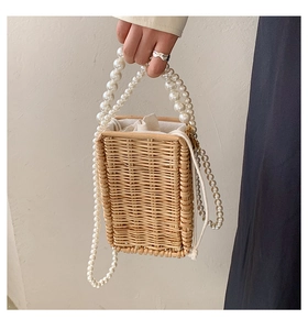 Detail of woven straw bag with large pearl handle and drawstring interior pocket