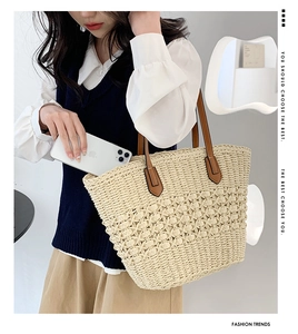 Détail d'un grand sac cabas en paille beige montrant l'espace intérieur avec un téléphone