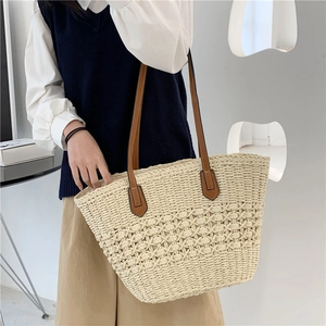 Détail d'un grand sac cabas en paille avec motifs ajourés et anses en cuir marron