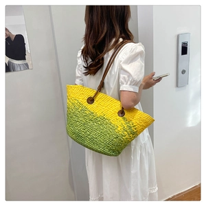 Detail of hand-woven gradient yellow and green tote bag with brown leather shoulder straps