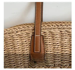 Détail de la texture paille tressée avec bandoulière en cuir marron et coutures blanches