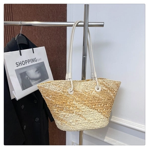 Detailed close-up of woven gradient straw tote bag with textured bicolor pattern and straps