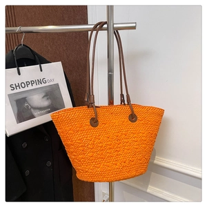 Detail of a large orange woven tote bag with brown leather straps for beach vacations