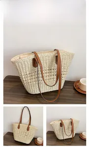 Gros plan du sac fourre-tout en paille tressée beige avec anses en cuir brun sur table