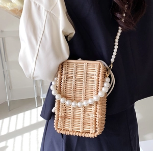 Fashionable woven straw crossbody bag with elegant pearl handle and pearl chain strap