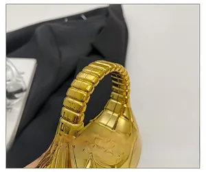 Détail du sac à main en acrylique doré avec poignée texturée et élégante chaîne dorée