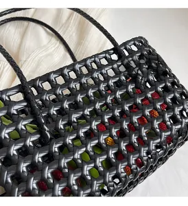 Close-up of black handwoven mesh bucket bag with strawberry decoration and slim handles