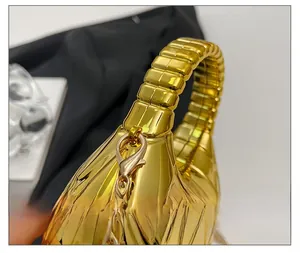 Détail de la pochette en acrylique doré avec finition métallique et poignée texturée