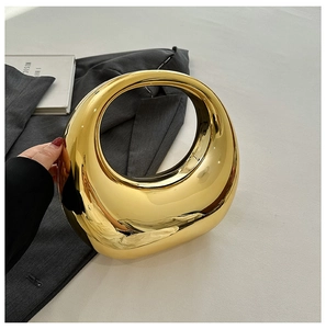 Close-up of golden metallic crescent clutch bag featuring a sleek mirror-like finish