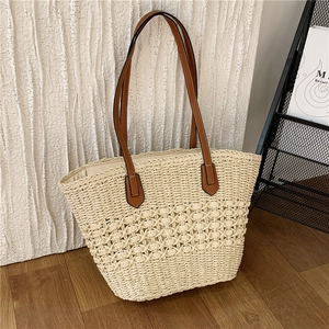 Sac fourre-tout minimaliste en paille tissée blanc crème avec bandoulière marron au sol