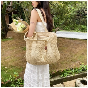 Detail of straw tote bag featuring wooden beads tassel and secure zip lining