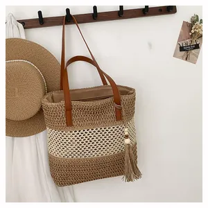 Detail of color-block straw bag with brown leather straps and wooden bead tassels