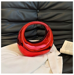 Close-up of red mirror finish acrylic evening bag with unique moon-shaped circular handle