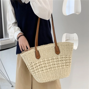 Grand sac cabas en paille avec motif ajouré et anses en cuir marron porté à l'épaule