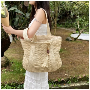 Close-up of large straw woven bucket bag with wooden beads and tassel detail