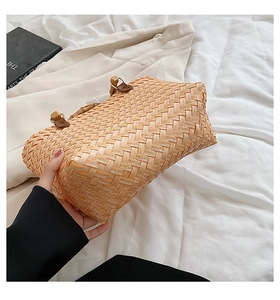 Detail of woven straw handbag featuring vintage bamboo handle and leather fastener
