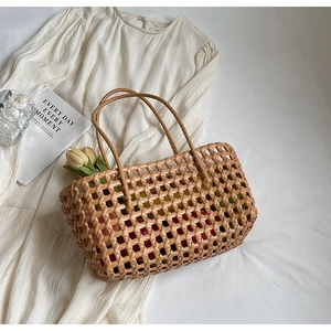Detail of hand-woven hollow grid beach bag with round handles on white fabric