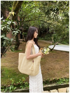 Detailed macro view of beige woven tote bag with wooden bead tassels for beach vacations
