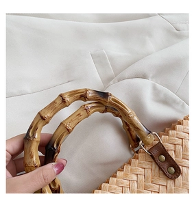 Detail of bamboo handle and leather buckle on a woven straw handbag for summer