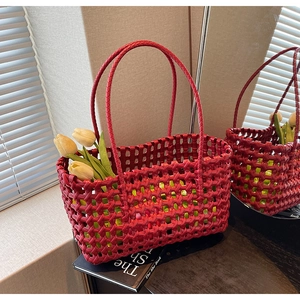 Detail view of a red hand-woven leather tote bag with elegant hollow texture and tulips
