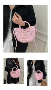 Pink woven straw beach bag with half-moon design, circular handle, and crossbody strap