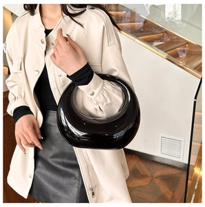 Chic glossy black acrylic crescent handbag shown in a street-style fashion setting