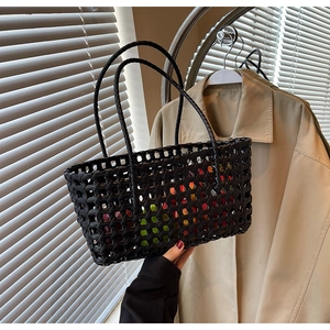 Close-up of black hollow woven basket bag with dual handles and colorful fruit inside