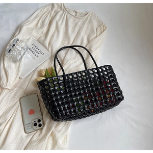 Detail of black woven tote bag featuring hollow diamond mesh and elegant long handles