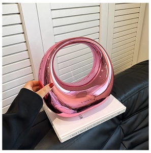 Detail of a bright pink metallic mirror clutch bag with a modern circular hollow design