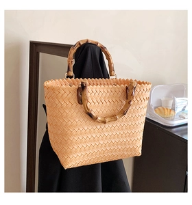Detail of woven straw handbag featuring vintage bamboo handle and metal ring connectors