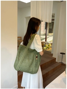 Close-up of green woven bucket bag featuring detailed texture and tassel with wood beads