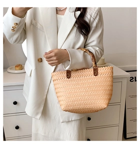 Detail of woven straw handbag featuring vintage bamboo handles and textured chevron pattern