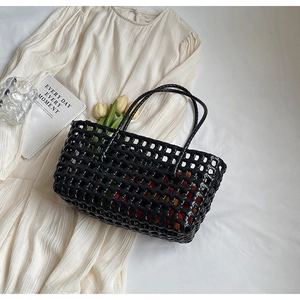 Detailed mesh texture of hand-woven black straw basket bag on elegant white dress