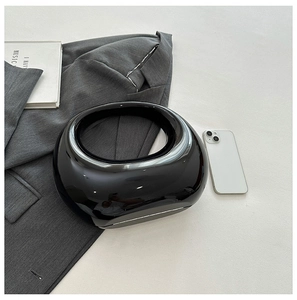 Detail of minimalist black glossy crescent handbag with a circular cutout handle