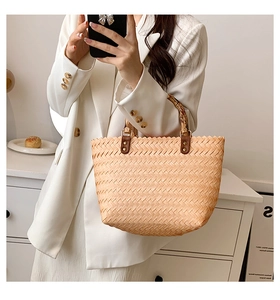 Close-up of woven straw handbag featuring vintage bamboo handle and leather details