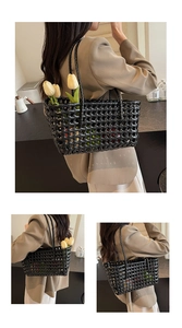 Close-up of black hollow woven basket bag with shoulder straps and interior floral decor