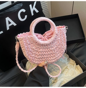 Detailed close-up of pink woven handbag with drawstring lining and matching shoulder strap