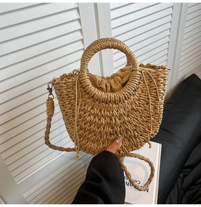 Close-up of woven straw handbag with circular handle and detachable braided shoulder strap