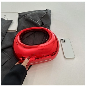 Close-up of glossy red mirror acrylic clutch with unique oval cutout handle detail